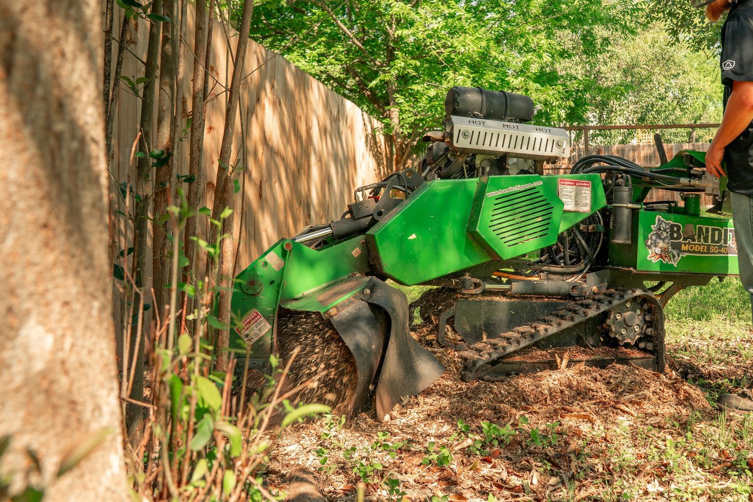 A worker operates a tree stump grinder